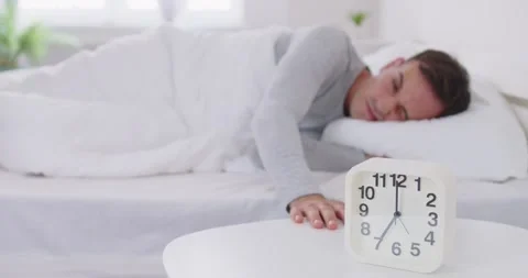 Sleeping man lying on bed in his bedroom and stopping alarm clock at home in the Stock Footage 292995587