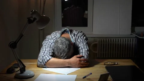 Sleeping man sits at a table at night 4K Video stock 130149025