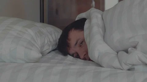 Sleeping man turns towards light while dreaming in a double bed with soft Stock Footage 100706591