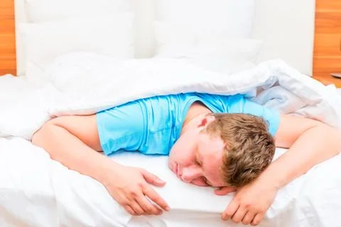Sleeping man on a white bed sheets Foto stock