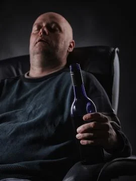 Sleeping middle aged alcoholic and wine bottle Fotos de archivo