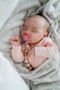 Sleeping newborn wrapped in soft blanket with pacifier. Warm light and intimate Fotos de archivo