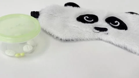 Sleeping pills and a panda shaped mask representing a remedy for insomnia, .. Stock Footage 335141658