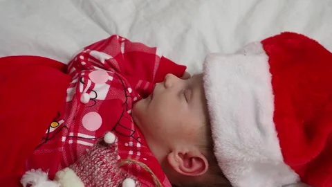 Sleeping, two week old, newborn, baby boy wearing a crocheted Santa hat wit.. Видео 293730846