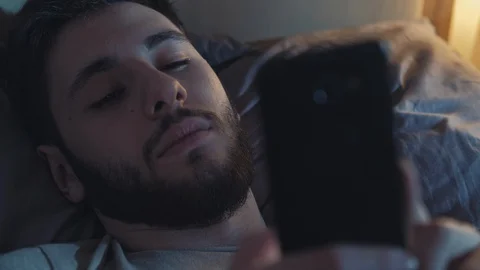 Sleepless night bored man using smartphone bed Vidéo 130012088