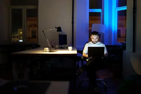 Sleepless programmer work on laptop at night. Young specialist in eyewear with 写真素材