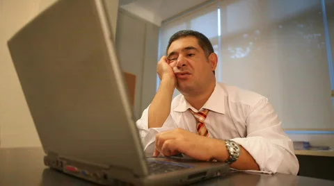 Sleepy businessman using laptop in office Stock Footage