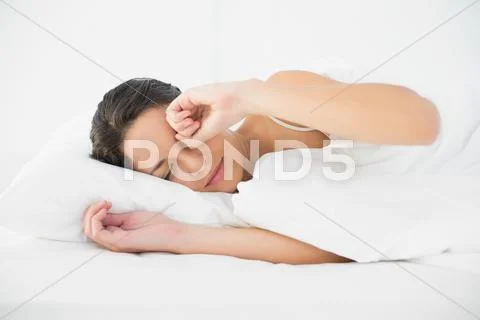 Sleepy casual brunette waking up and rubbing her eyes Stock Photos