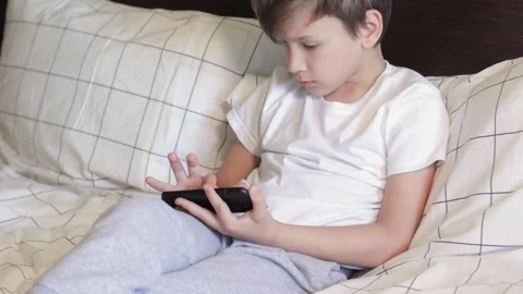 Sleepy child uses smartphone instead of sleep Stock Footage 161084444