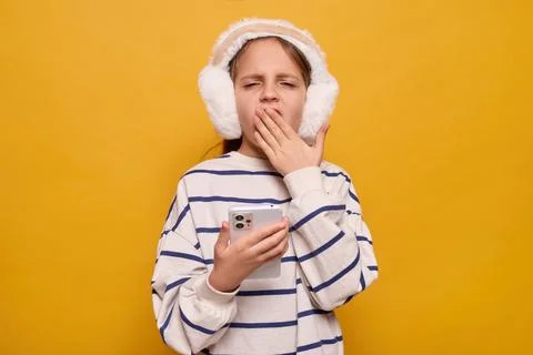 Sleepy exhausted small child using smartphone for browsing online yawning whi Stock Photos