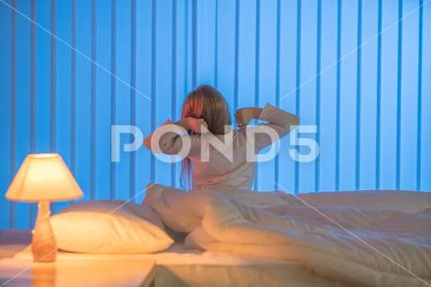 The sleepy girl sitting in the bed. Evening night time Stock Photos