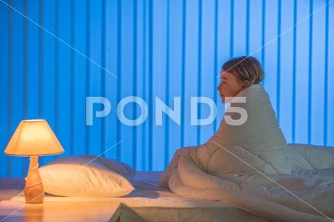 The sleepy girl sitting on the bed. Evening night time Stock Photos