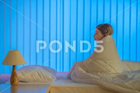 The sleepy girl sitting on the bed. Evening night time Stock Photos
