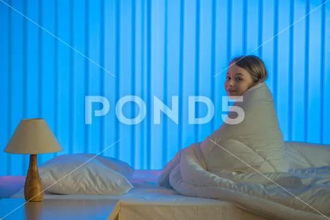 The sleepy girl sitting on the bed. Evening night time Stock Photos