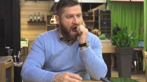 Sleepy, impatient, man, sitting at table, in pub, cafe, indoor, steadicam shot Vídeo Stock 73067545