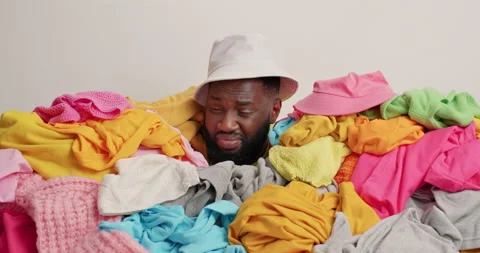 Sleepy man awakes after doing housework poses around big stack of unfolded Stock Footage 157336161