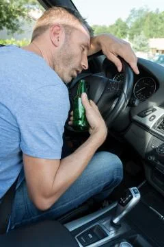 Sleepy man drinking beer while driving a car Stock Photos