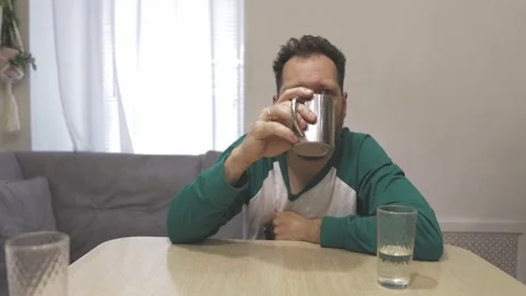 A sleepy man drinks coffee in the kitchen in the morning Video stock 194411479