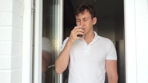 Sleepy man drinks cup of coffee for awakening on balcony Stock Footage 245750869