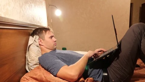 Sleepy man with laptop computer in bed late at night. 4k Vidéo 82286917
