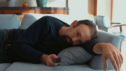 Sleepy man lying on the sofa and watching TV Stock Footage 121581818