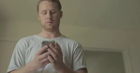 Sleepy man texts on smartphone at home Stock Footage