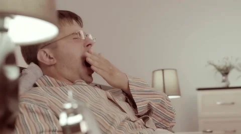 Sleepy man yawns while sitting in his bed Stock-Footage 68421114