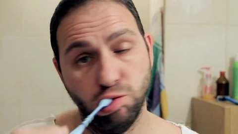 Sleepy middle-aged man in the bathroom brushes his teeth without toothpaste c Video stock 128038995