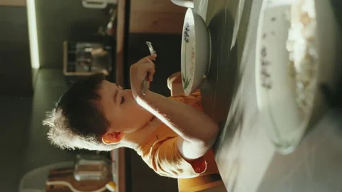 Sleepy six year old boy eating bowl of oatmeal for breakfast. The concept of a Stock Footage 257682998