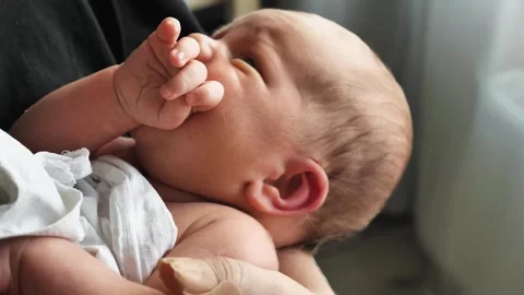 A sleepy three-week-old newborn, his tiny fist clenched near his mouth Stock Footage 345555025