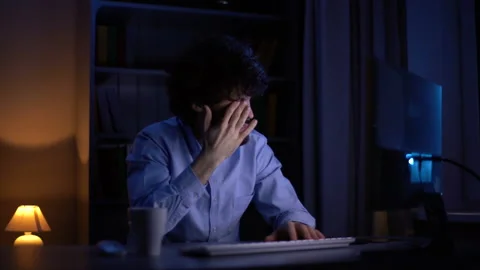 Sleepy young bearded man working late at night on computer rubbing eyes at home Video stock 146177131
