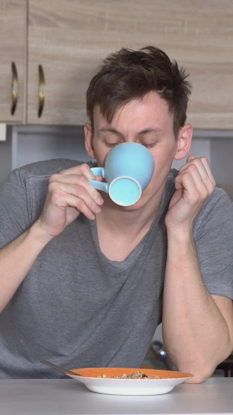 Sleepy young man struggling to stay awake while having breakfast, feeling tired Video stock 341677053