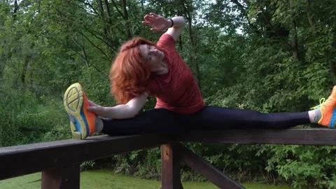 Slender athletic lady stretches her muscles on the shore of the pond Stock Footage 135089448