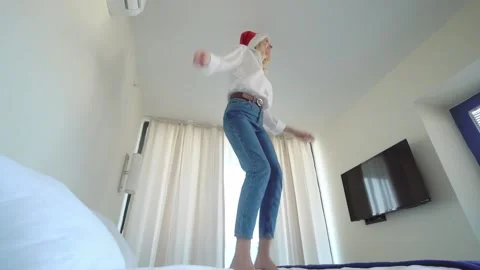Slender beautiful girl dancing in a Santa Claus hat on the bed. Видео 201961653