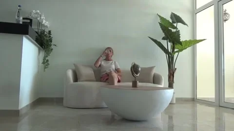 A slender blonde sits on a sofa in a hotel lobby Stock Footage 338386217
