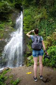 A slender brunette with a backpack and a camera stands near a picturesque wat Foto stock