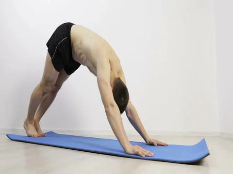 Slender fit man doing yoga on exercise mats in fitness hall.  Stock Footage 73077028