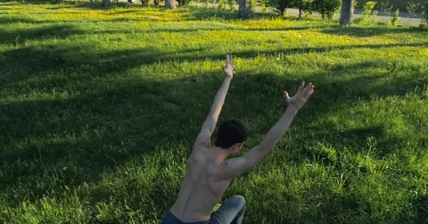 Slender handsome bare-chested man practicing yoga in the park. Brunette guy Vídeo Stock 77063327