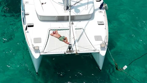 Slender man enjoying sunbathing on white sailing yacht on tropical vacation. Stock Footage 315850928
