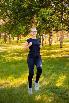 Slender woman doing jogging on the spot. Sports activities in the summer park Stock Photos