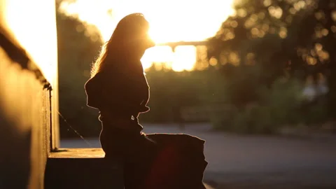 Slender young girl posing in a back-light. Silhouy of a slender girl. Stock Footage 91151236