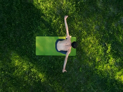 Slender young man practicing yoga in park. Top view. Copter footage. Video stock 79792510