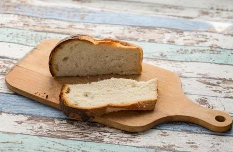 Slice and bread loaf on cutting board on turquoise vintage table Stock Photos