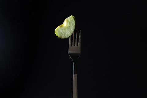A slice of apple on a fork on a black background.  Stock Photos