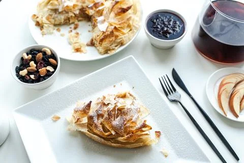A slice of apple pie or a dessert of phyllo pastry on a white plate on a light Stock Photos
