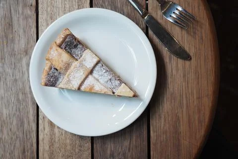 Slice of apple pie on a white plate placed on a wooden table Stock Photos