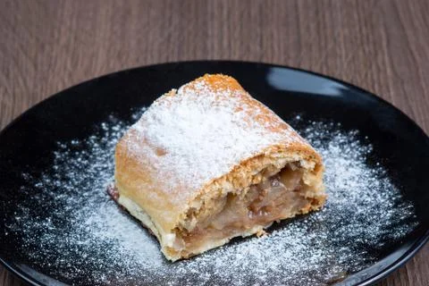 Slice of apple strudel on a black plate Stock Photos