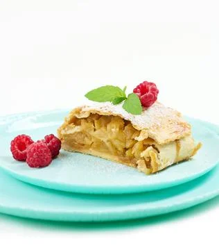 Slice of apple strudel on a round plate, white background Stock Photos
