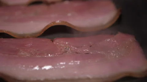 Slice of bacon fried on grill pan slow motion Stock Footage 147578828
