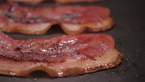 Slice of bacon fried on grill pan slow motion Stock Footage 147578897